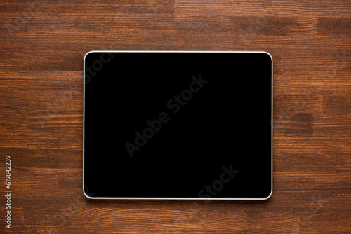 Top view of tablet on the wooden background.