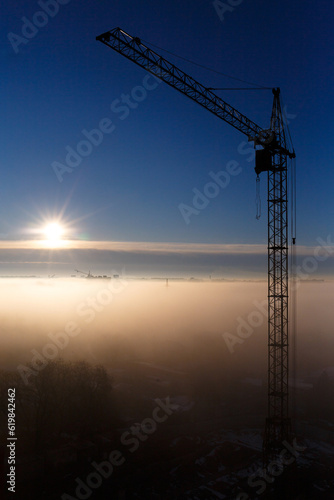 Construction crane in the fog at dawn
