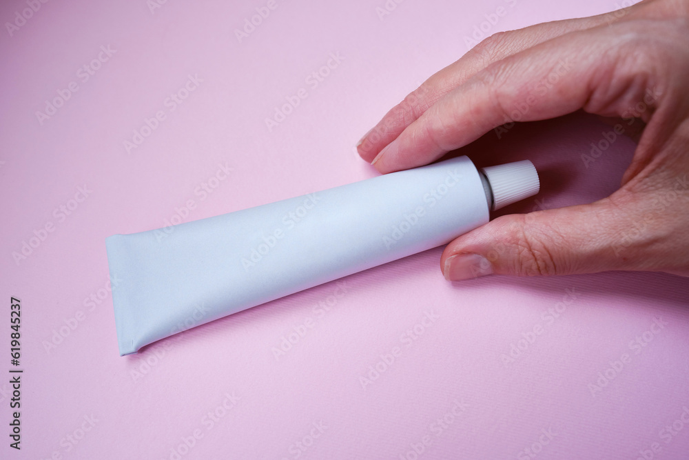 Stylish metal tube for drug or cosmetic branding - cream, gel, skin care, toothpaste. Container for cosmetic bottles in the hands of a girl. Minimalism Stylish metal tube for drug or cosmetic branding - cream, gel, skin care, toothpaste. Container for cosmetic bottles in the hands of a girl. Minimalism