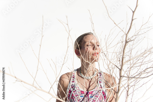 Photograph of a beautiful woman creating shadows on her face using a dry desert plant. 