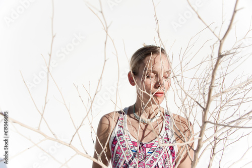 Photograph of a beautiful woman creating shadows on her face using a dry desert plant. 