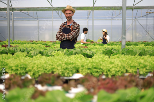Farmer checking plant health in greenhouse system and harvesting. Farmer inspect farm products quality and fresh vegetables in greenhouse hydroponics farm with happy for food supply chain.