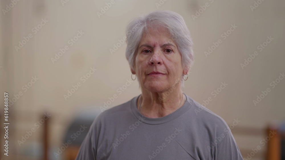 Elderly woman close-up face looking at camera with neutral expression. An older female caucasian person with gray hair Elderly woman close-up face looking at camera with neutral expression. An older female caucasian person with gray hair