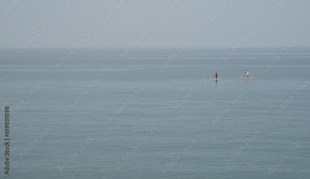 Unrecognized people canoeing in the sea in the morning. People exercising in the ocean.