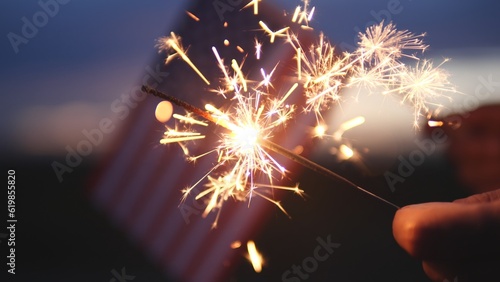 Happy Independence Day July 4th, Labor Day. Hand holding sparklers fireworks celebration fourth of July, 4th of July with America flag background. Concept Holiday, Freedom, Memorial, Veterans Day