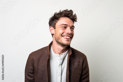 Medium shot portrait photography of a grinning man in his 20s wearing a chic cardigan against a white background © Hanne Bauer