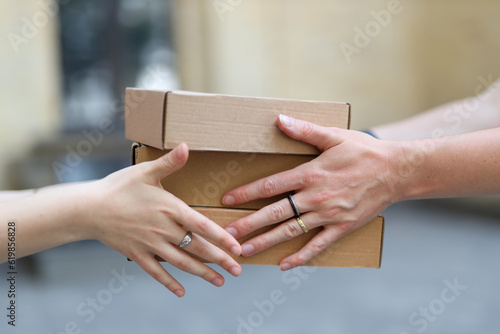 Passing cardboard boxes from hand to hand close-up. © Andrii Zastrozhnov