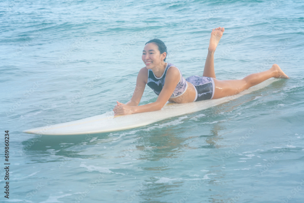 Asian women wearing swimsuits hobby happy fun Practice surfing waves on a board in the sea is an exciting water sport on the beach in Thailand.