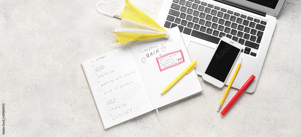 Obraz premium Mobile phone with laptop, small umbrella and notebook on grunge background. Weather forecast concept