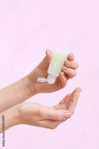 Woman applying sanitizer on pink background