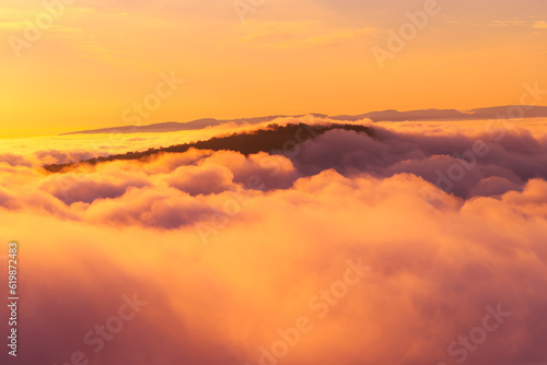 Aerial view of Morning sunrise above the mountains with mist around , Mountains fog and morning sun in winter at Pha Mo Edang ,Sisaket province,Thailand.red light.