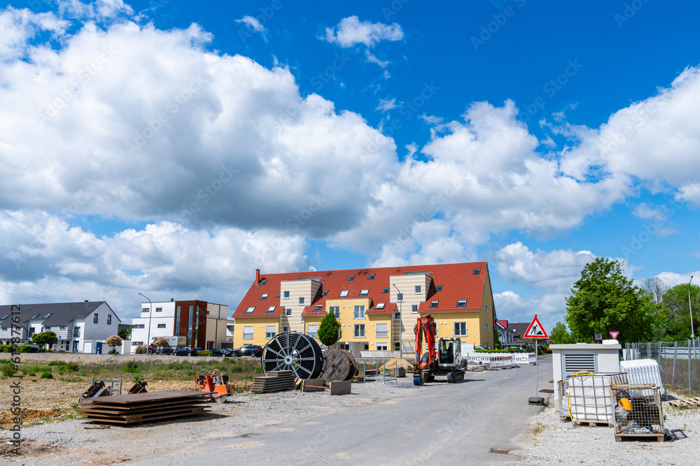 Construction site on the background of a residential area under a blue sky with white clouds. Construction site on the background of a residential area under a blue sky with white clouds.