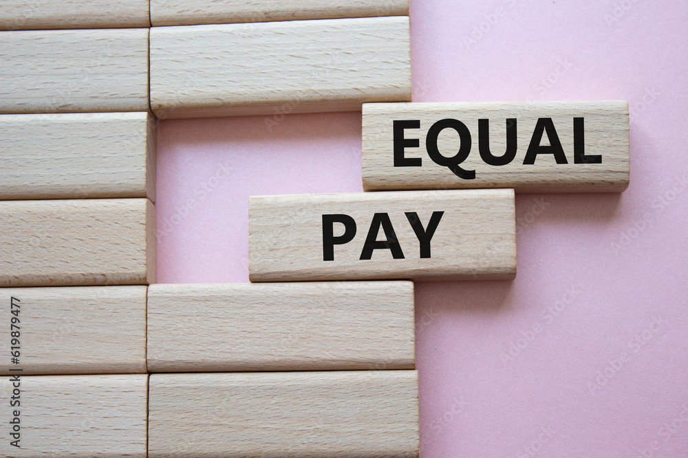 Equal Pay symbol. Wooden blocks with words Equal Pay. Beautiful pink background.Business and Equal Pay concept. Copy space. Equal Pay symbol. Wooden blocks with words Equal Pay. Beautiful pink background.Business and Equal Pay concept. Copy space.