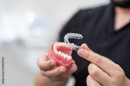 Cuadro en lienzo Doctor installing clear aligners on plastic lower human jaw model to show simple