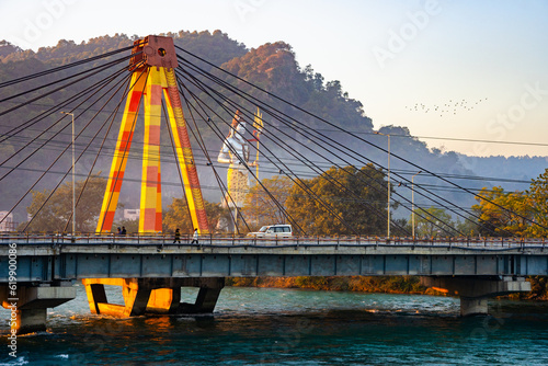 A statue of Shiva stands behind the Haridwar Bridge as the Ganga flows underneath.  photo