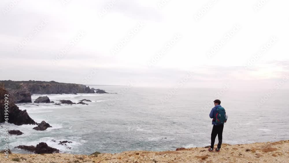 Man standing on the edge of a cliff watching the west coast of Portugal. A place to think and learn about the power of the Atlantic Ocean. 4k video Man standing on the edge of a cliff watching the west coast of Portugal. A place to think and learn about the power of the Atlantic Ocean. 4k video