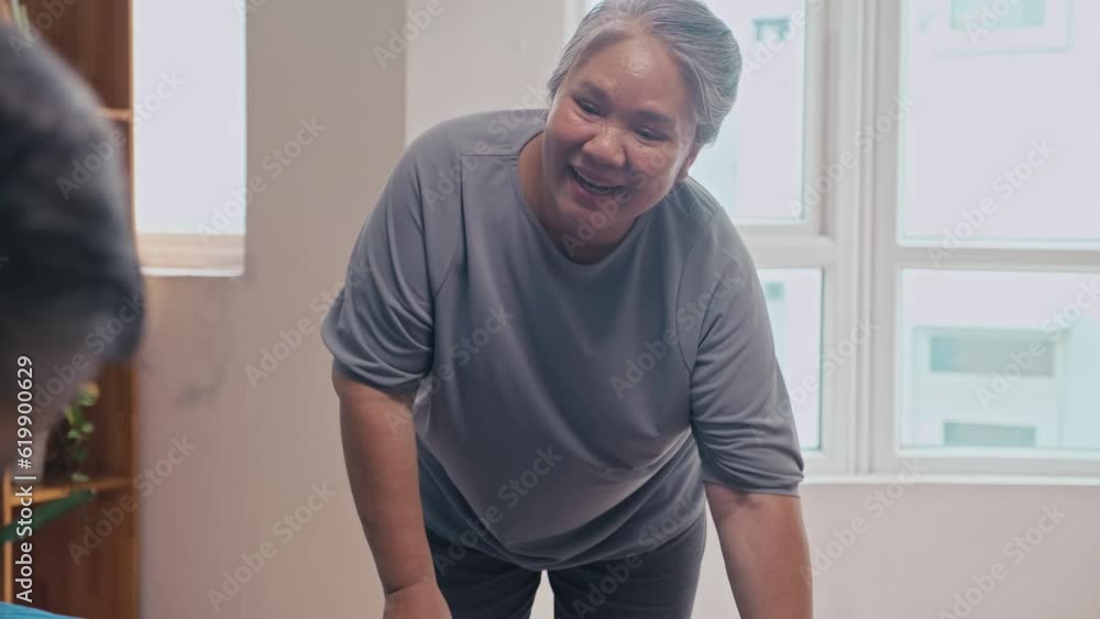 Over the shoulder shot of man changing linen on bed together with senior wife Over the shoulder shot of man changing linen on bed together with senior wife