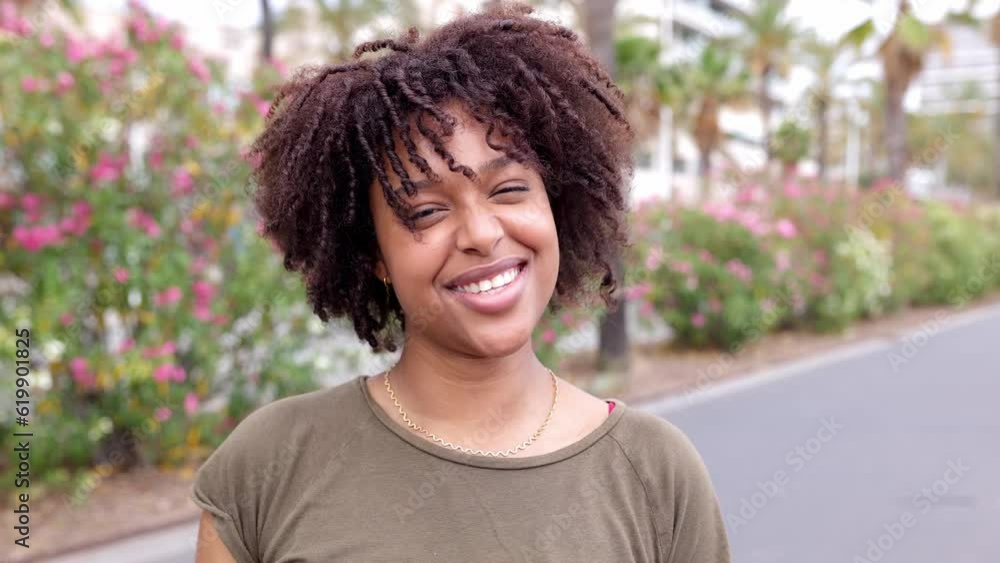 Portrait of joyful african american woman with curly hair smiling at camera standing outdoors. Portrait of joyful african american woman with curly hair smiling at camera standing outdoors.