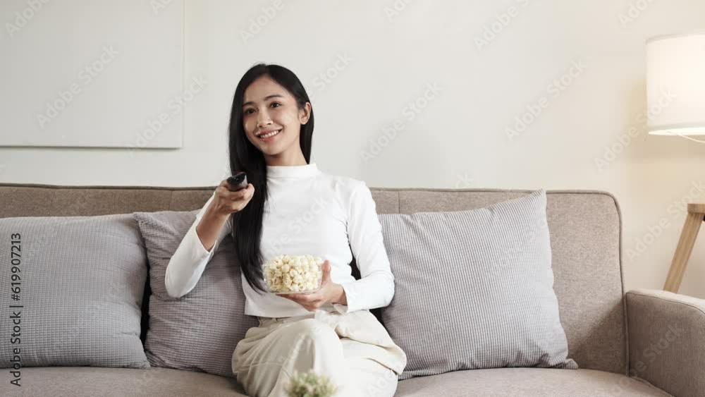 Asian young beautiful woman watching fun movie on television at home. Attractive casual girl feel happy and relax, sit on sofa having fun watch comedy video on TV in house. Activity lifestyles concept Asian young beautiful woman watching fun movie on television at home. Attractive casual girl feel happy and relax, sit on sofa having fun watch comedy video on TV in house. Activity lifestyles concept