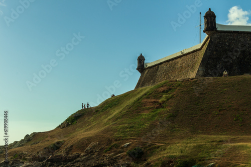 small people to scale with the "Farol da barra" hill. People having fun, Afternoon at Salvador, bahia. fortress sentries