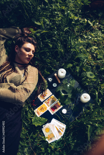 Fotografie girl lies in the grass next to the fortune telling table on a grass, where there