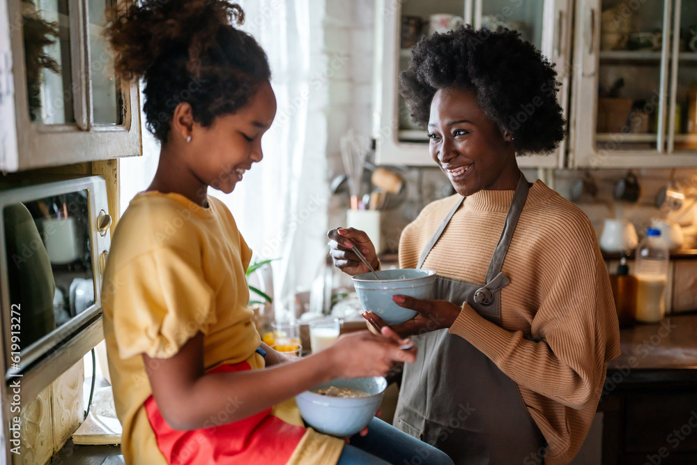 Happy black mother and daughter having breakfast and spending quality time together in kitchen