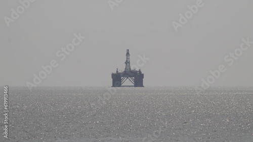 Offshore oil platform drilling site or oil rig project seen far in the middle of the sea. photo