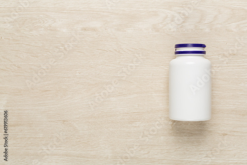 Plastic bottle with vitamins on wooden background, top view