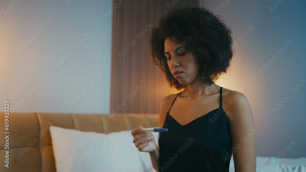 Sad young woman holding negative pregnancy test sitting on bed, feeling upset Sad young woman holding negative pregnancy test sitting on bed, feeling upset
