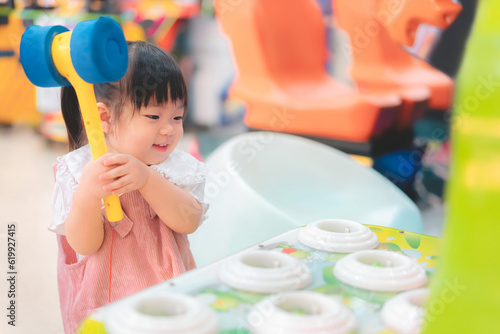 Asian little girl playing whack a mole arcade game at  amusement park, She happy and enjoy, Learning and active of kids concept.