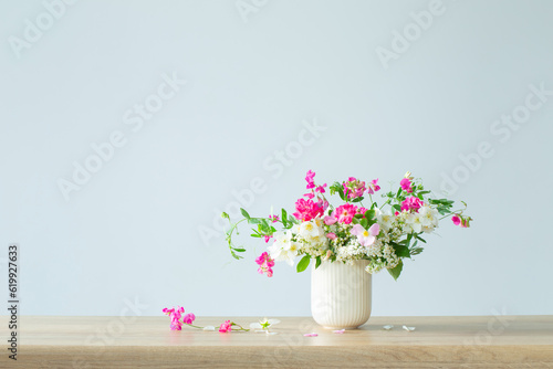 summer flowers in ceramic cup on light background