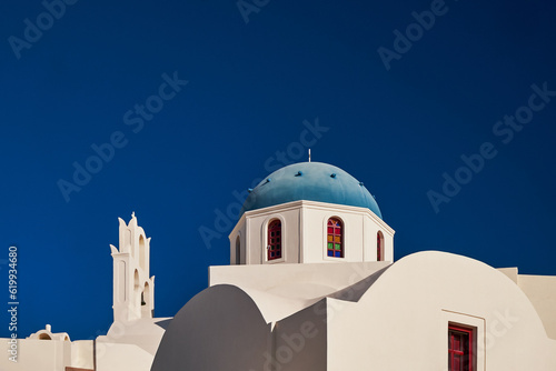Panoramic Aerial View of Oia Village and Blue Dome Church in Santorini Island, Greece - Traditional White Houses in the Caldera Cliffs - Sunset