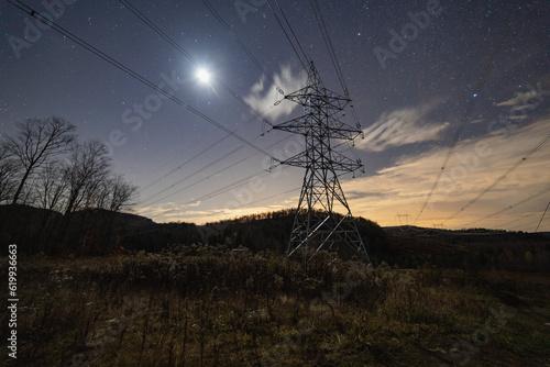 vue sur un pylône électrique en métal avec plusieurs lignes suspendues dans la nature lors d'une nuit avec la lumière de la lune