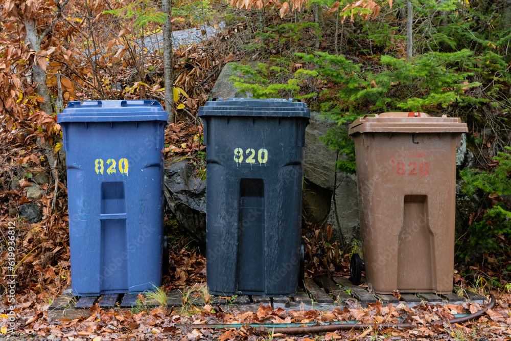 trio de bac à ordures au bord du chemin prêt à être ramassés lors d'une journée d'automne avec une côte derrière trio de bac à ordures au bord du chemin prêt à être ramassés lors d'une journée d'automne avec une côte derrière