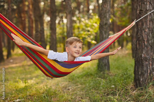 Cute little blond caucasian boy having fun with multicolored hammock