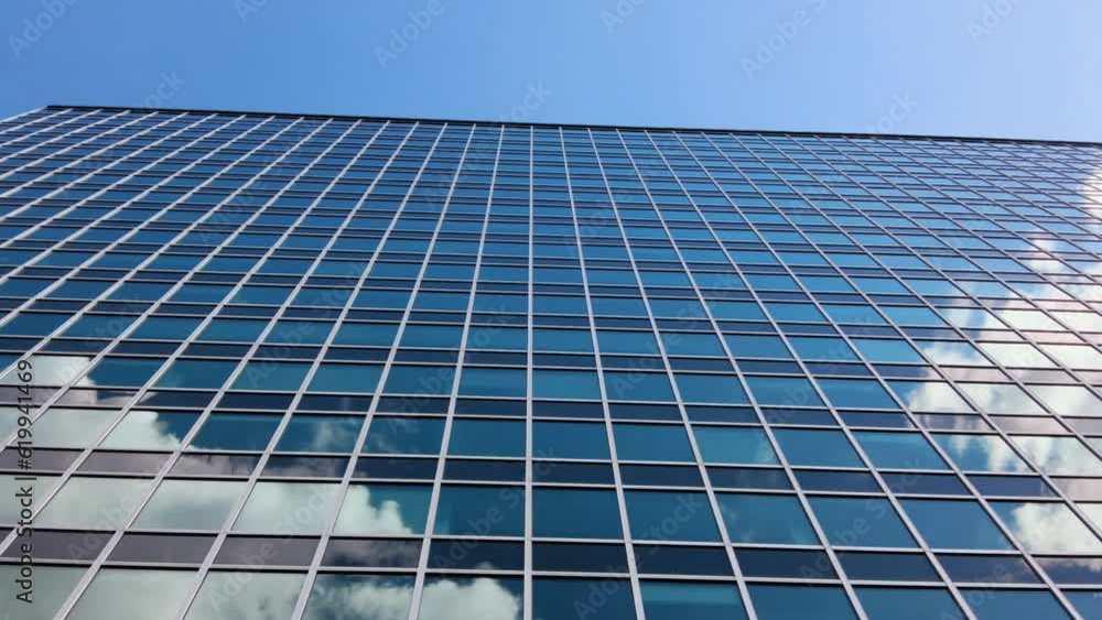 Reflection of the sky on the windows of the building. Corporate building against blue sky with clouds. Reflection of the sky on the windows of the building. Corporate building against blue sky with clouds.