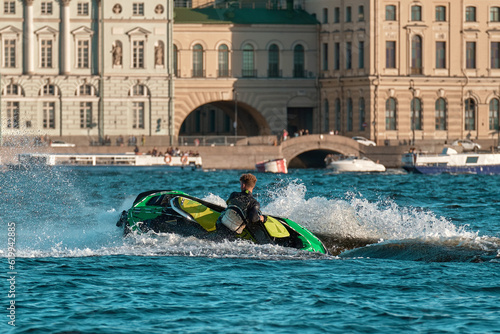 A man rides a jet ski on the river. A male performs various tricks on a aquabike. photo