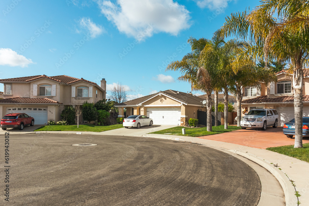 Beautiful houses with nicely landscaped front the yard, and cars parked on a sidewalk in small town in California.