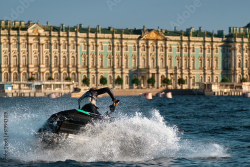 A man abruptly turns around on a jet ski, splashing water in different directions. Athlete extreme rides on a jet ski performing various tricks on the city river. photo