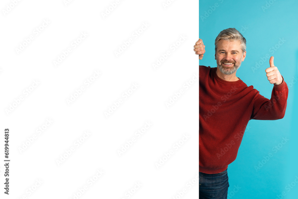 Positive middle aged man standing by huge advertisement board, mockup Positive middle aged man standing by huge advertisement board, mockup