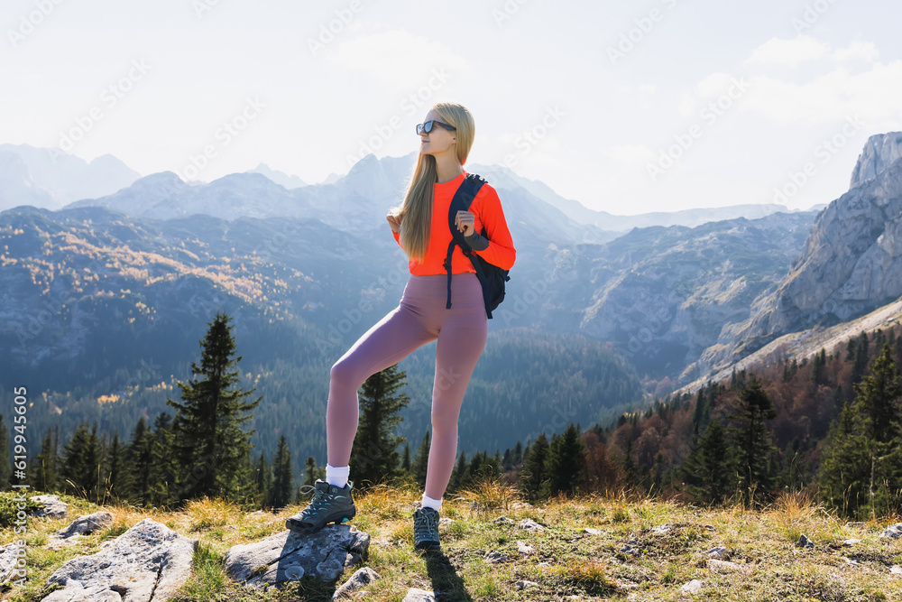 A young woman while walking on mountain trails in sunny weather