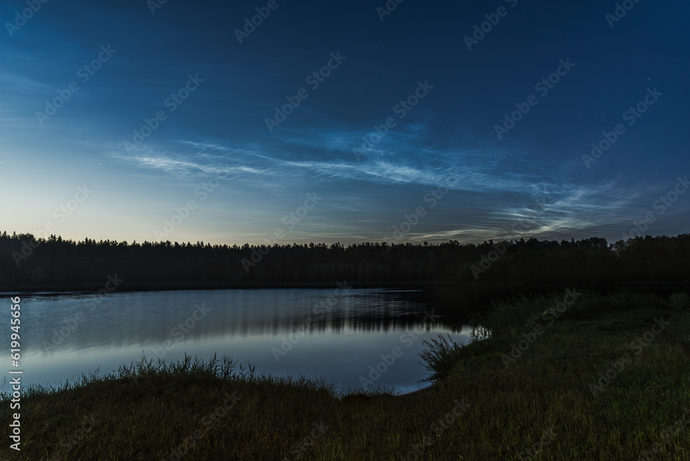 Fototapeta premium Noctilucent clouds over the forest lake in Latvia at July night