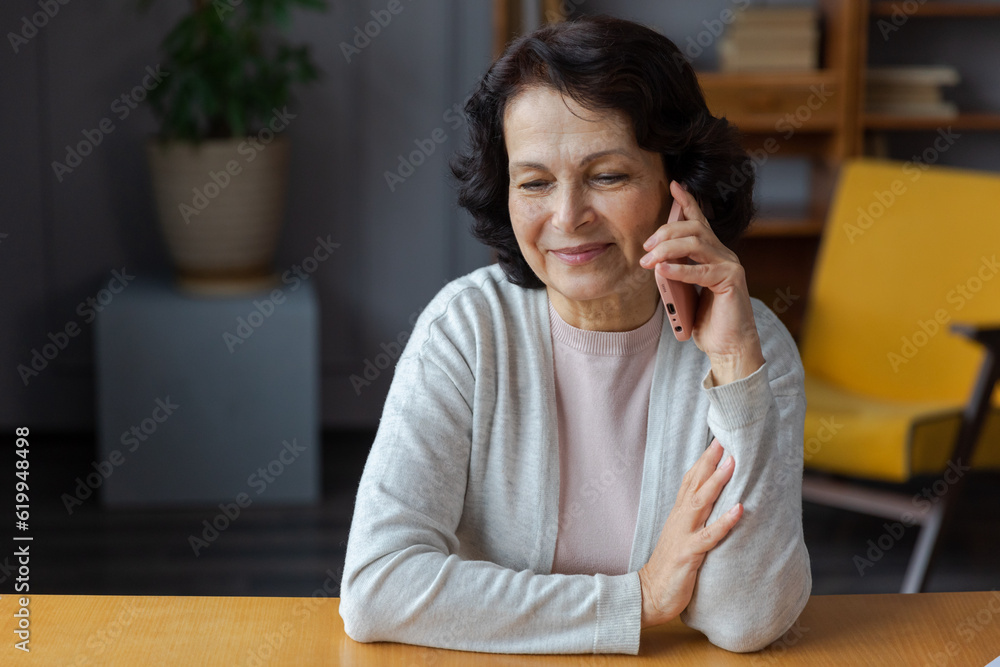 Happy middle aged senior woman talking on smartphone with family friends. Older mature lady with cell phone chatting with grown up children, resting in at home. Older generation modern tech usage Happy middle aged senior woman talking on smartphone with family friends. Older mature lady with cell phone chatting with grown up children, resting in at home. Older generation modern tech usage