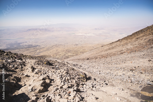 View from the slope of the mountain and the Ararat volcano to the valley and the plain, a slope with stones during the day in the mountains