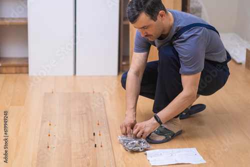 Modern furniture assembling service employee in coveralls putting smooth wooden planks to rack designed for office interior carpentry industry and business