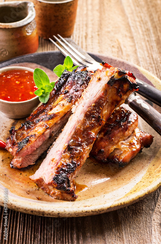 Barbecue veal spare ribs sliced with hot honey chili marinade served as close-up on a rustic design