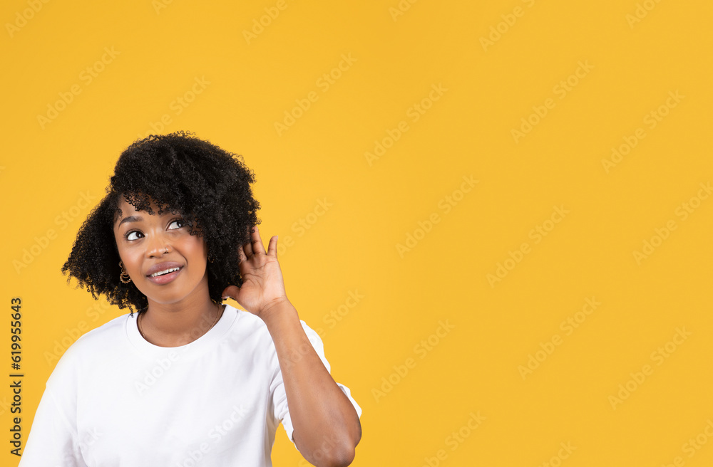 Happy interested millennial black woman in casual listening and looking at empty space