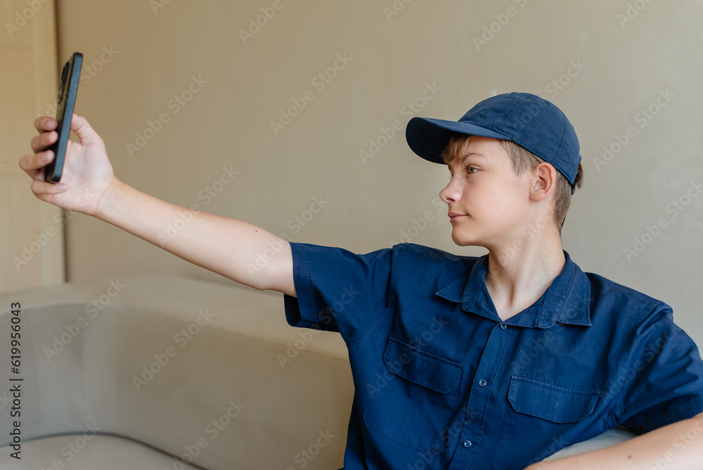 Teen boy making selfie photos on smartphone in living room at home Teen boy making selfie photos on smartphone in living room at home