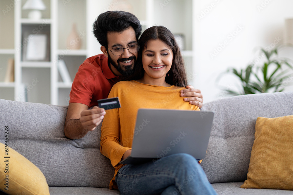 Indian Couple Making Online Shopping With Laptop And Credit Card At Home Indian Couple Making Online Shopping With Laptop And Credit Card At Home