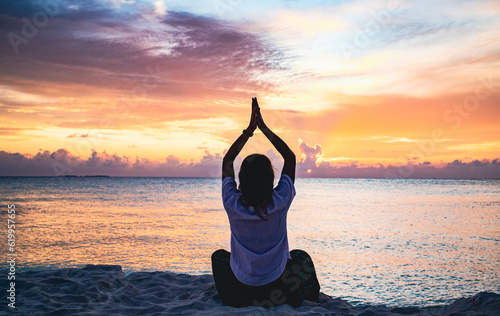 woman doing yoga at sunset on tropical beach